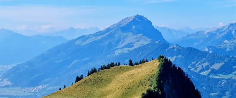 A sunny alpine ridge with Swiss mountains in the distance.